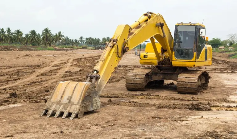 A yellow and black excavator on dirt ground