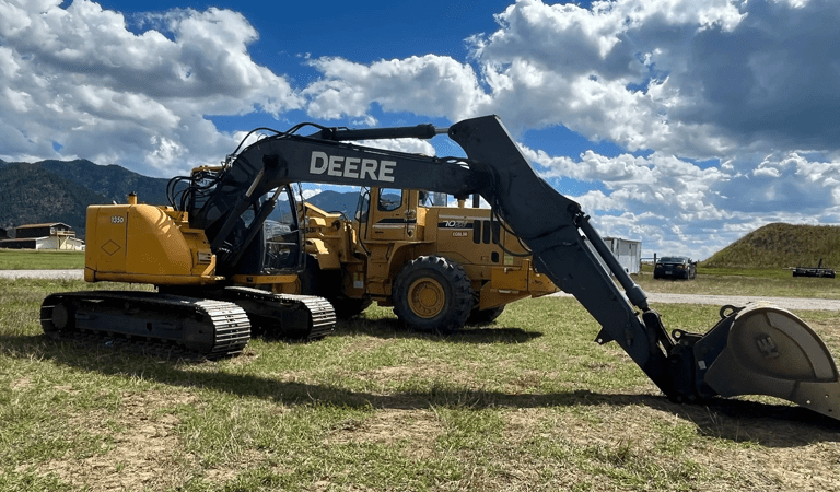 A yellow and black tractor is parked in the grass