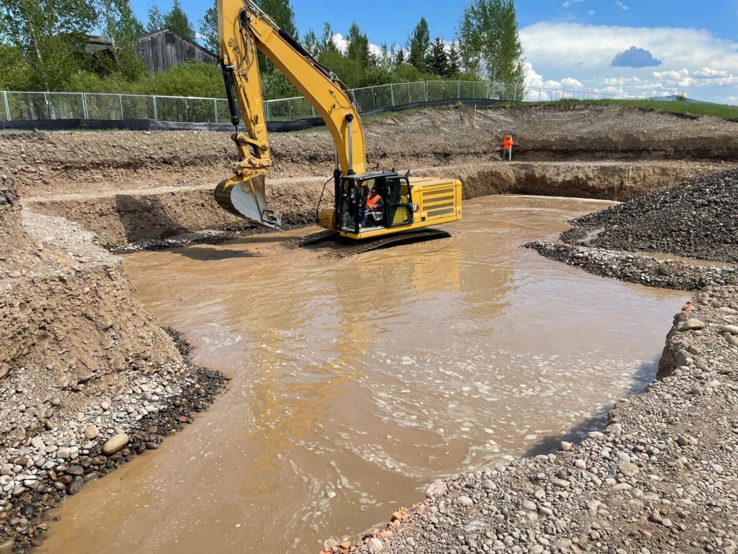 A yellow and black excavator is in the dirt