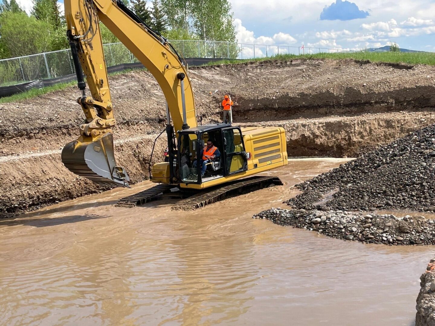 A yellow and black excavator is in the mud